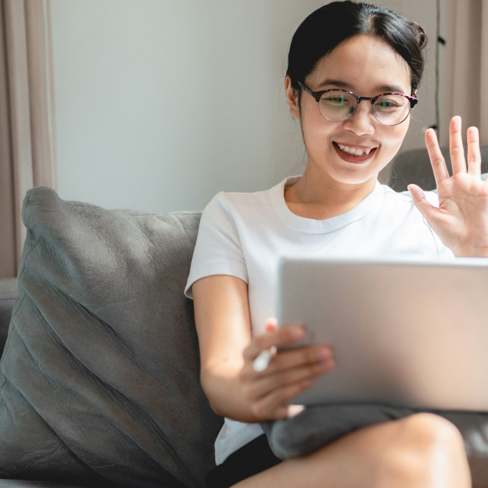 Woman on laptop waving at screen