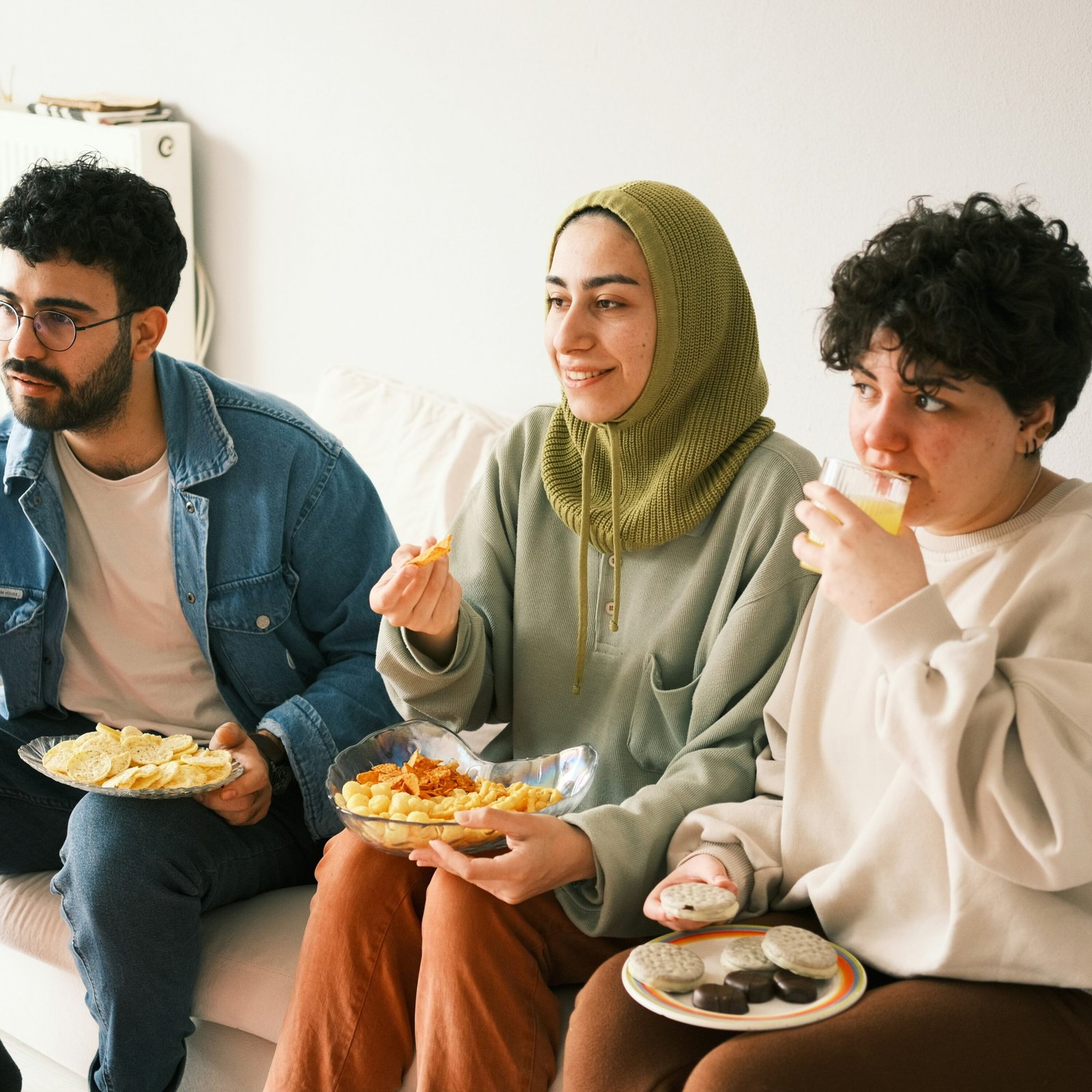 People drinking and eating, smiling on sofa